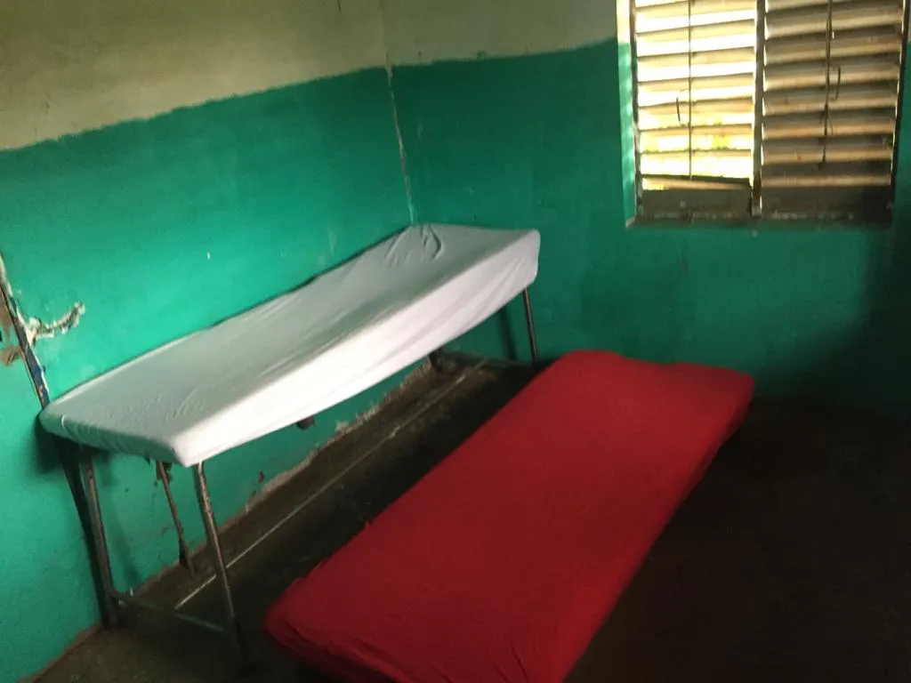 Two examination couches in the green-painted room of the health post