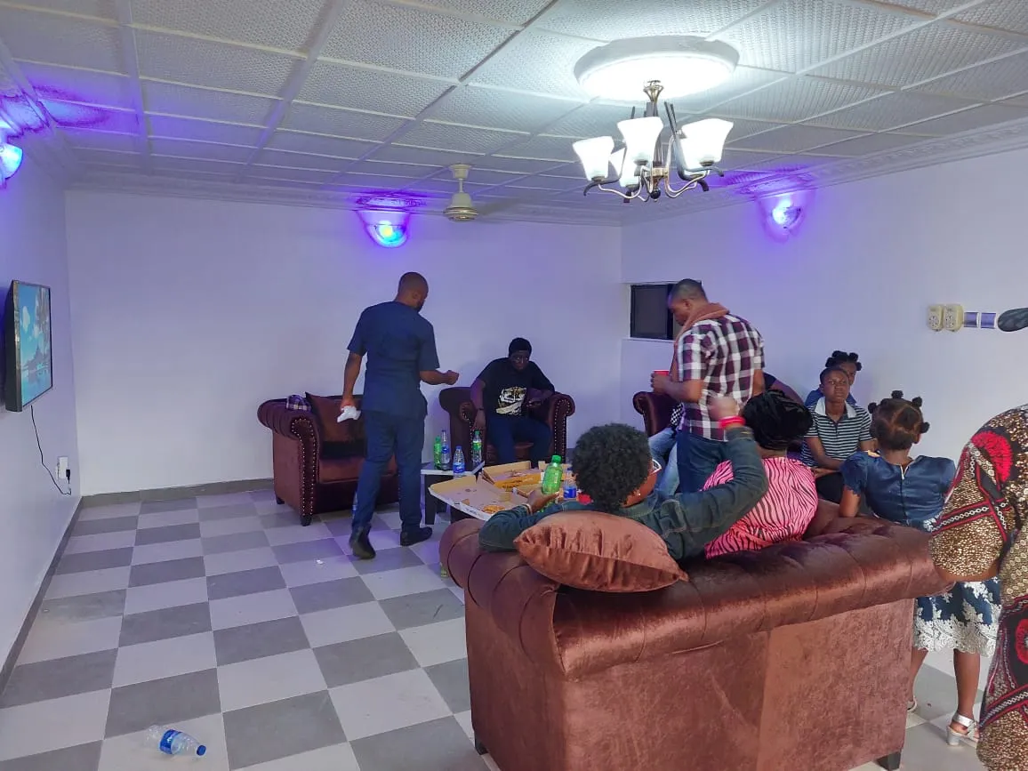 The furnished common room of the Lagos shelter, with people sitting together on sofas