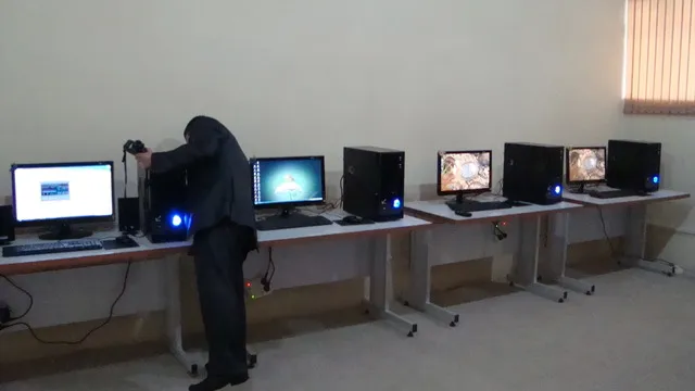 A student at a row of desktop computers on wheeled desks in the computer workshop