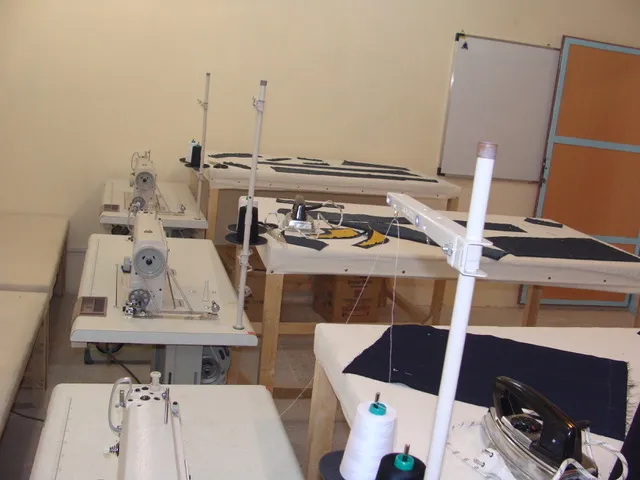 The sewing workshop: industrial sewing machines and cut fabric pieces laid out on work tables