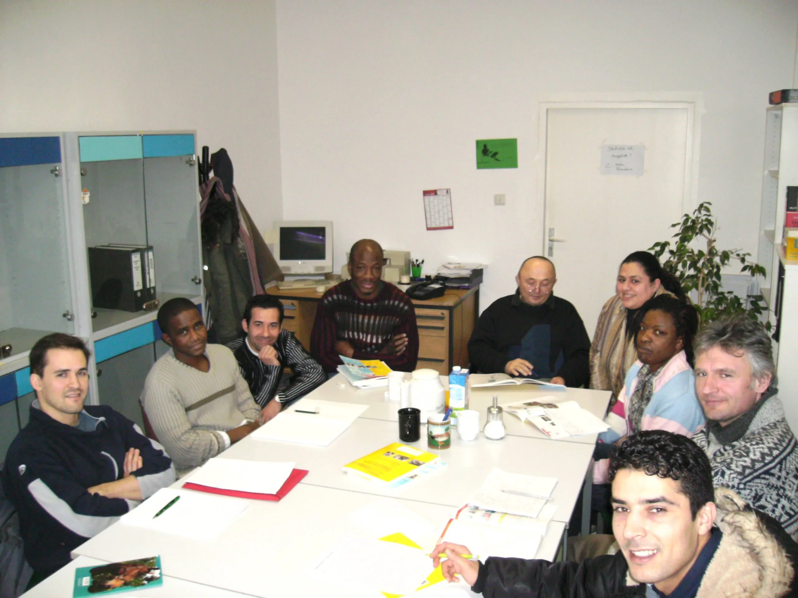 A group of adults seated around a table at the KUB centre with papers and leaflets in front of them