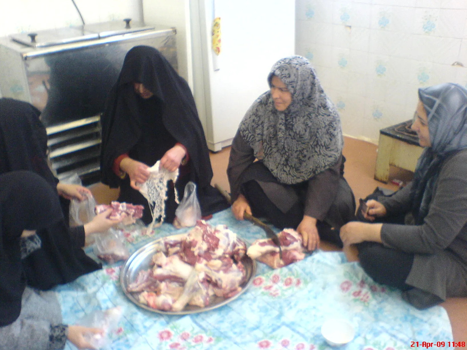 Frauen sitzen am Boden um ein Tablett mit Fleisch und portionieren es zur Verteilung in Beutel