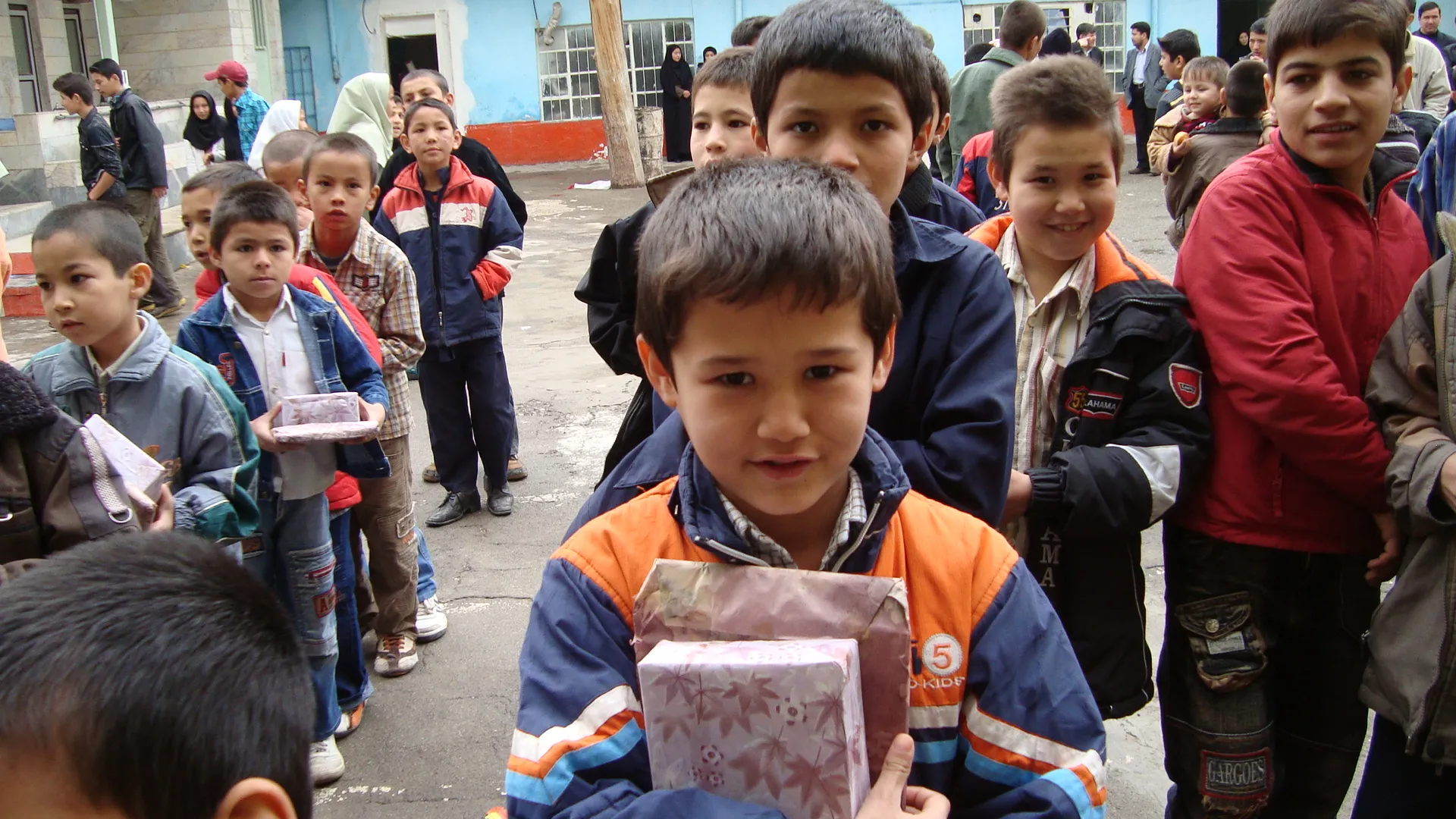 Boys queueing in the courtyard, each holding a wrapped parcel