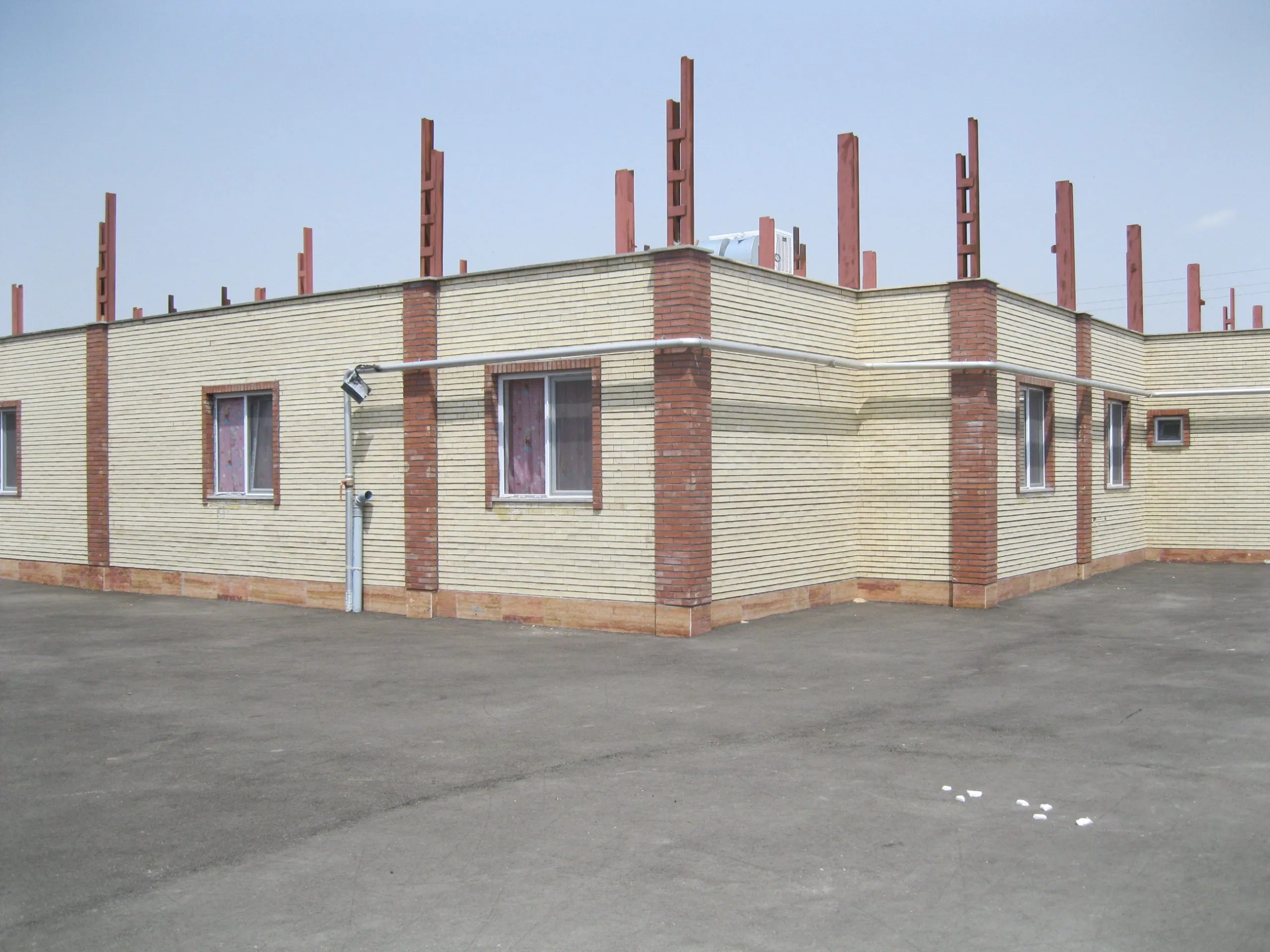 The newly built single-storey brick building, with reinforcement columns still projecting above the roof