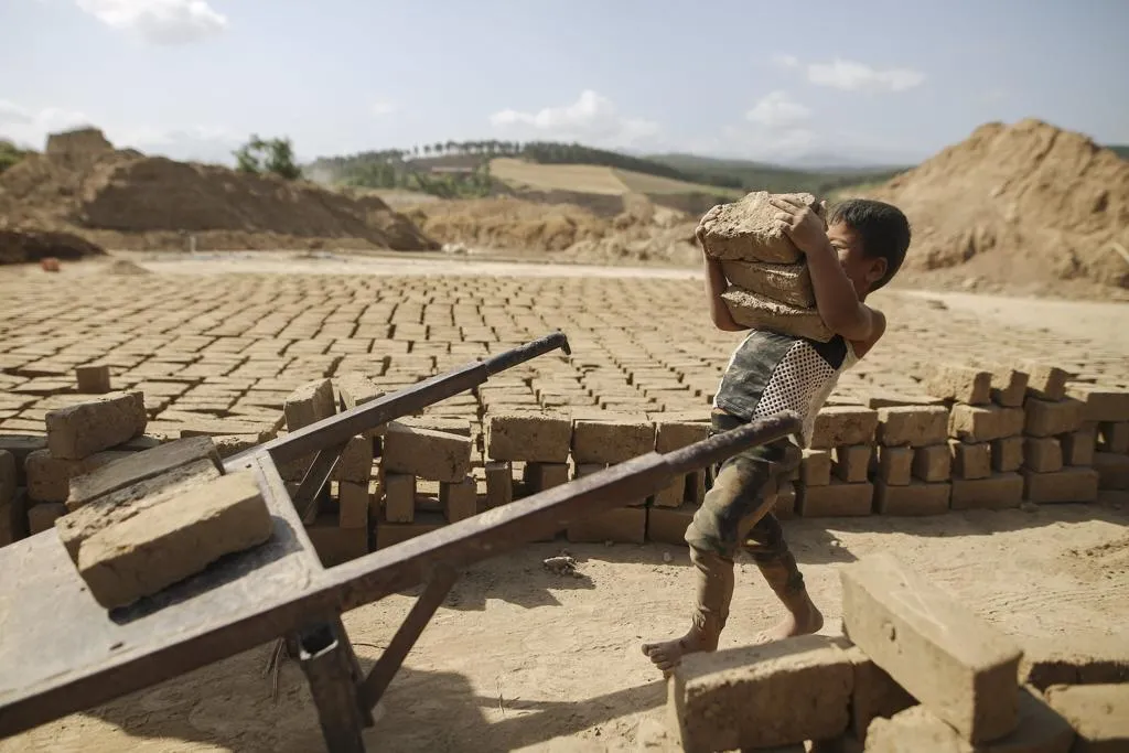 A young boy carrying bricks