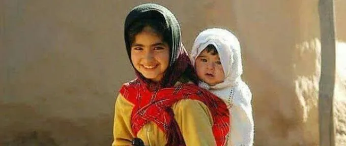 A young girl carrying a bay on her back