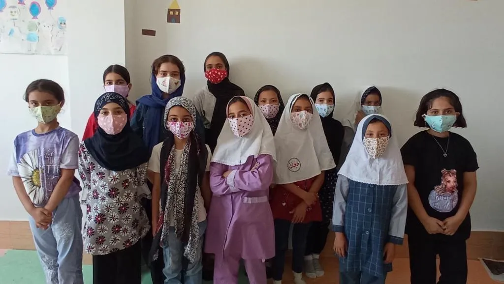 Eine Gruppe Mädchen mit Mund-Nasen-Schutz steht gemeinsam in einem Klassenraum des Zentrums