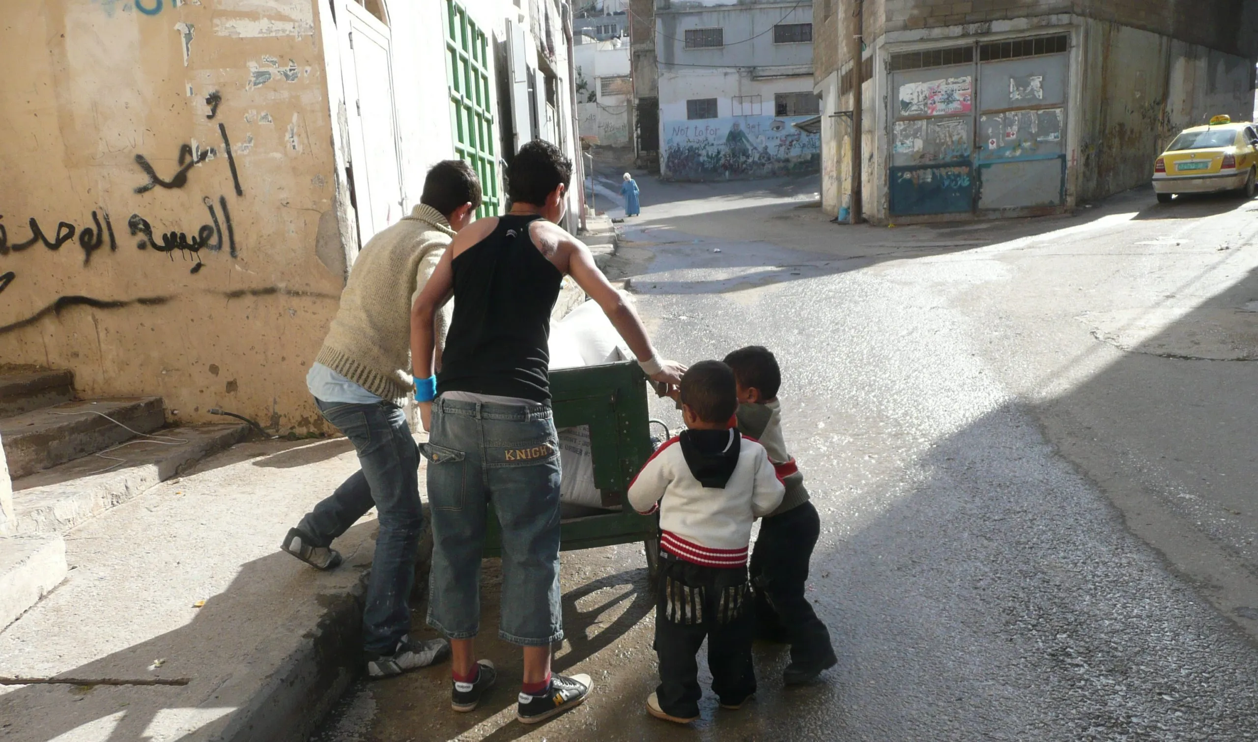 Boys pushing a handcart loaded with sacks up a village street