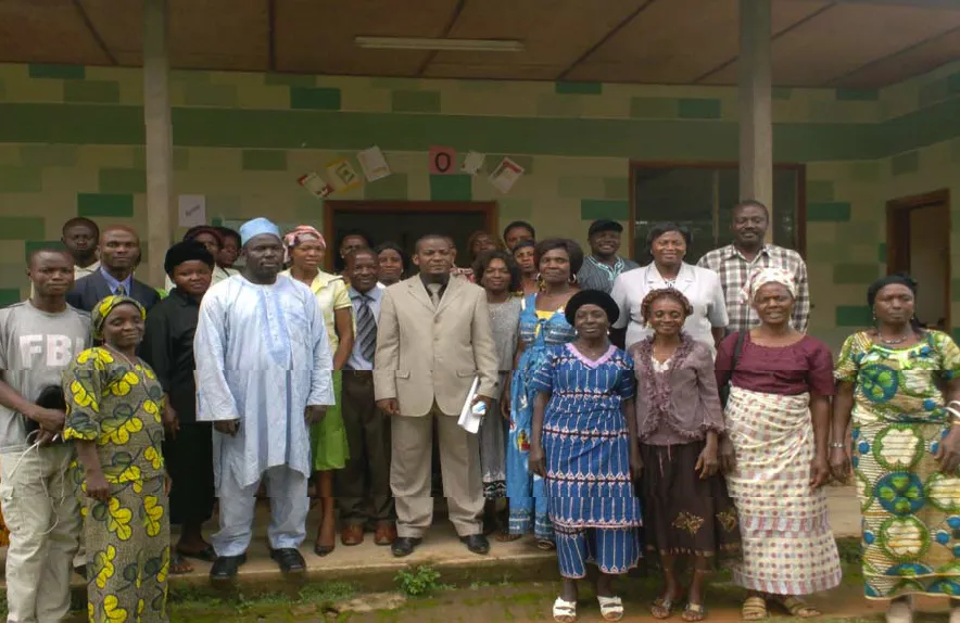 A large group of women and men from the project standing together in front of the project building
