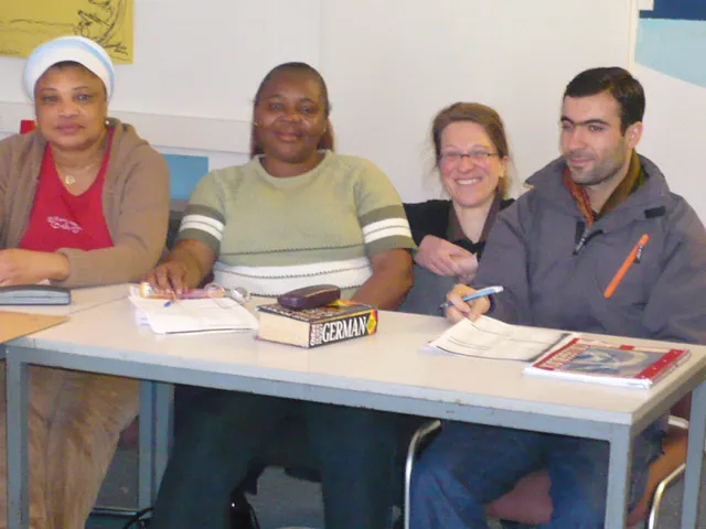 Four adult learners at a desk in the German class, a German dictionary and notebooks in front of them